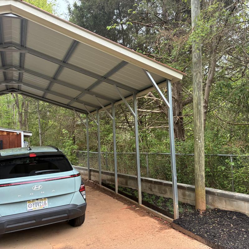 Metal carport with support posts on concrete driveway