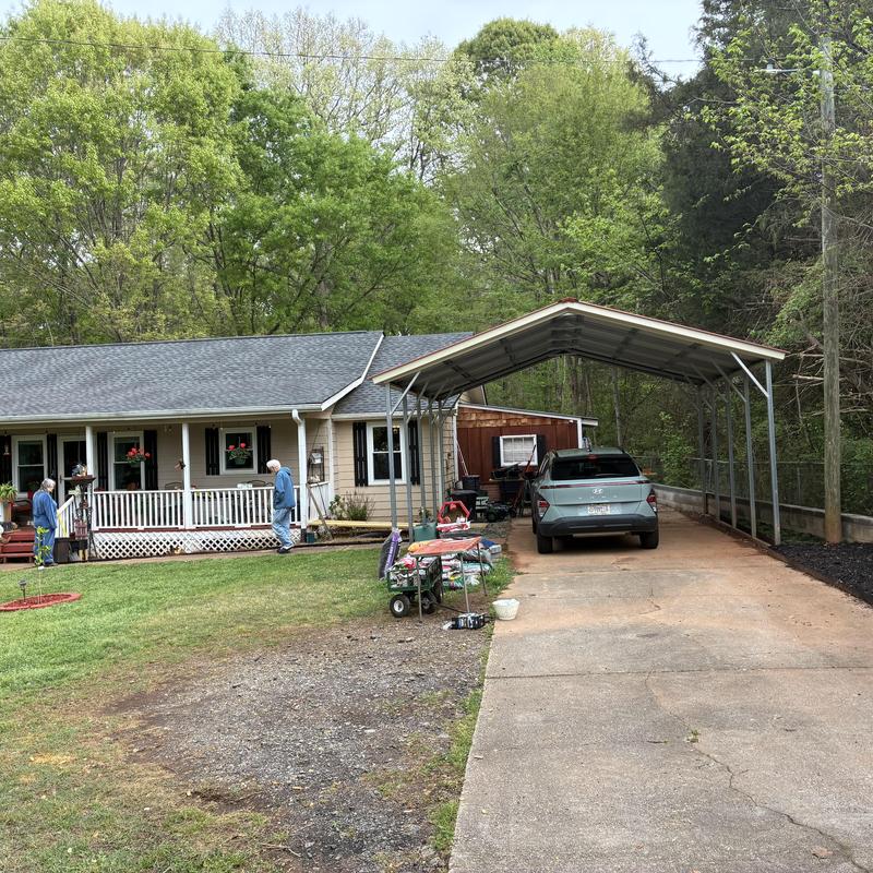 Metal carport structure with concrete driveway parking