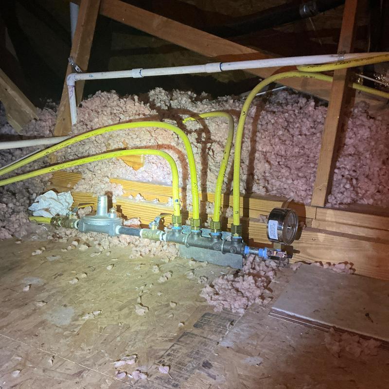 Gas manifold with yellow supply lines in attic space