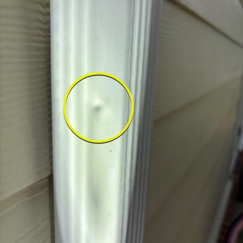 Vinyl siding metal trim with dent marked by yellow circle