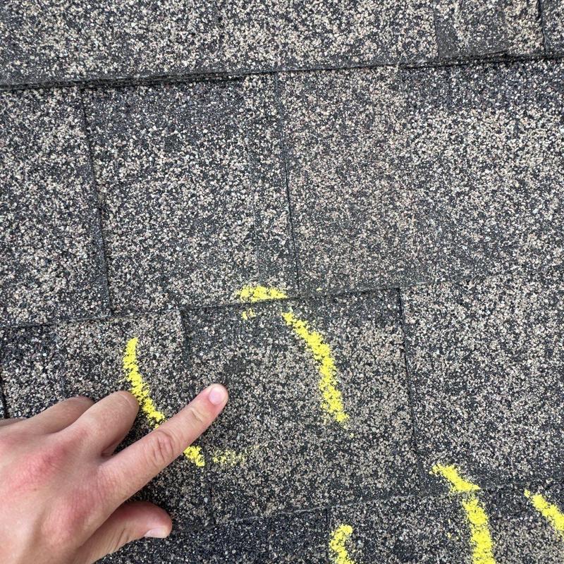 Asphalt roof shingle hail damage marked with yellow paint