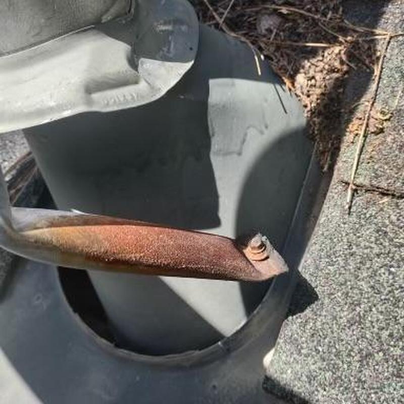 Roof vent with rusted mounting bracket on shingle roof