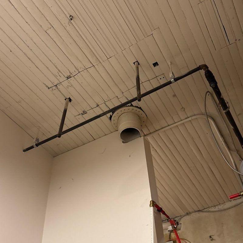 Exhaust duct and metal piping suspended from ceiling