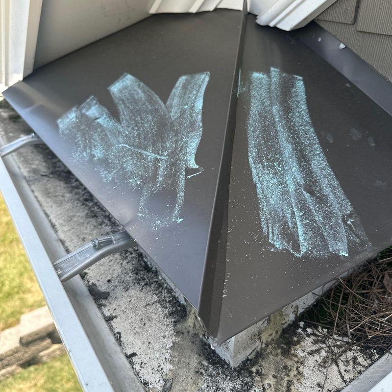 Metal roof edge with chalk markings on damage areas