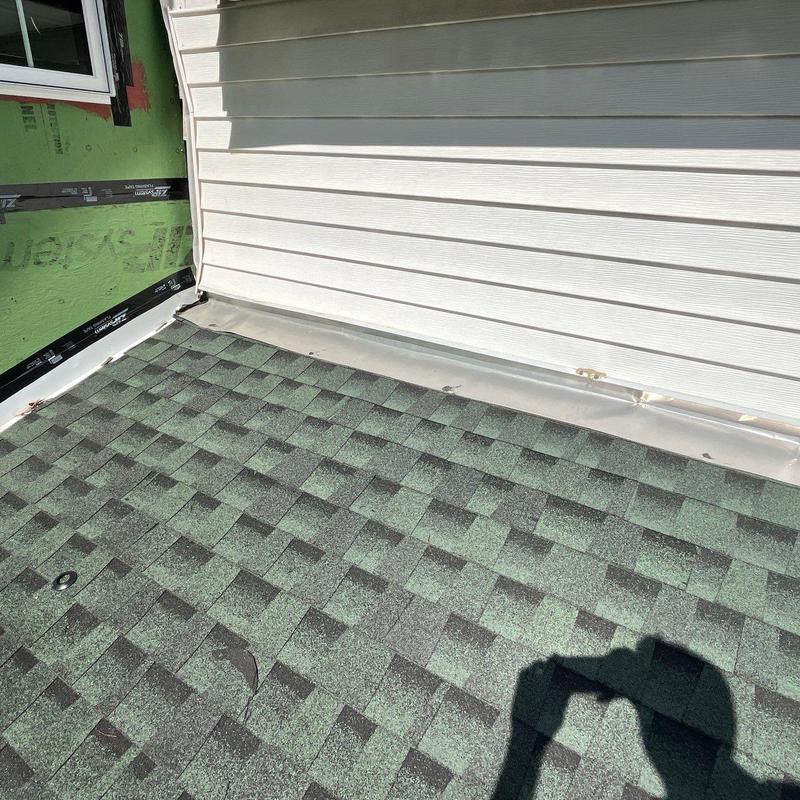 Asphalt shingle roof with damaged flashing near siding