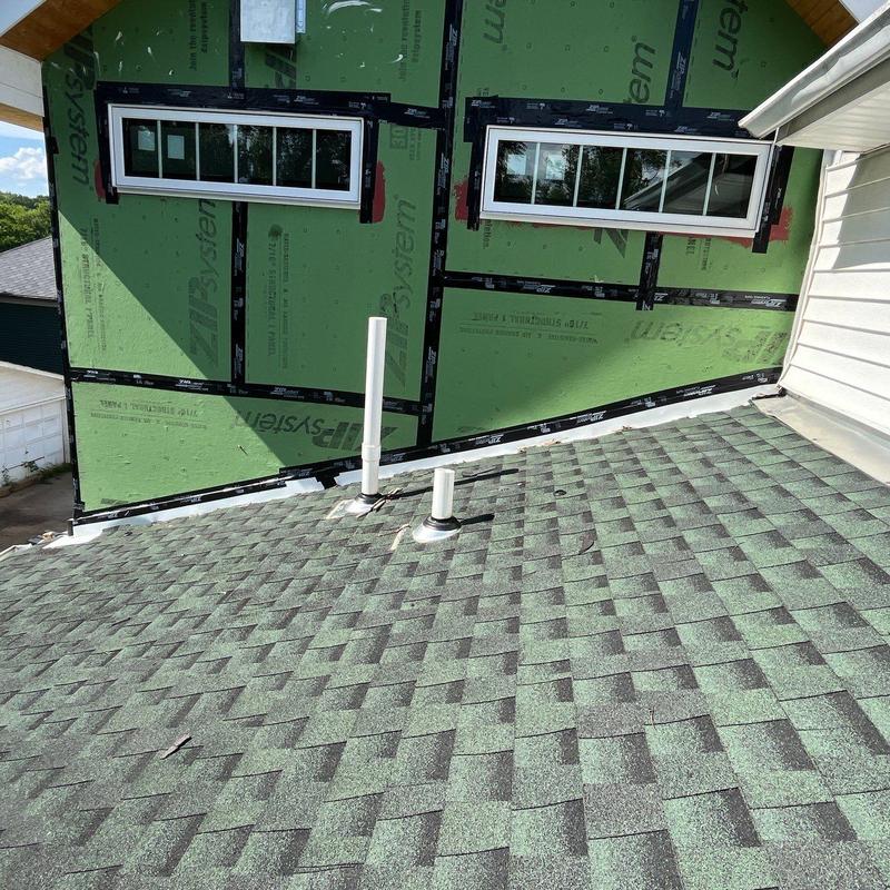 Asphalt shingle roof with pipe flashings and house wrap