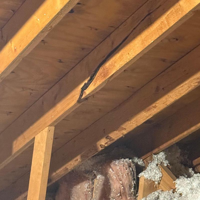 Roof joist with visible structural damage in attic