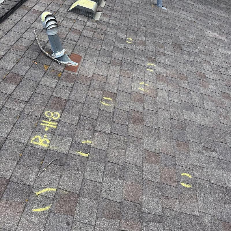 Asphalt shingles with hail damage marked for repair