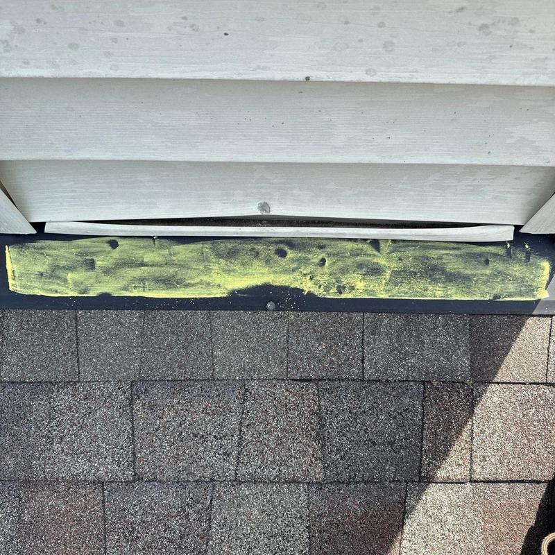 Roof flashing with chalk-marked hail damage on shingles