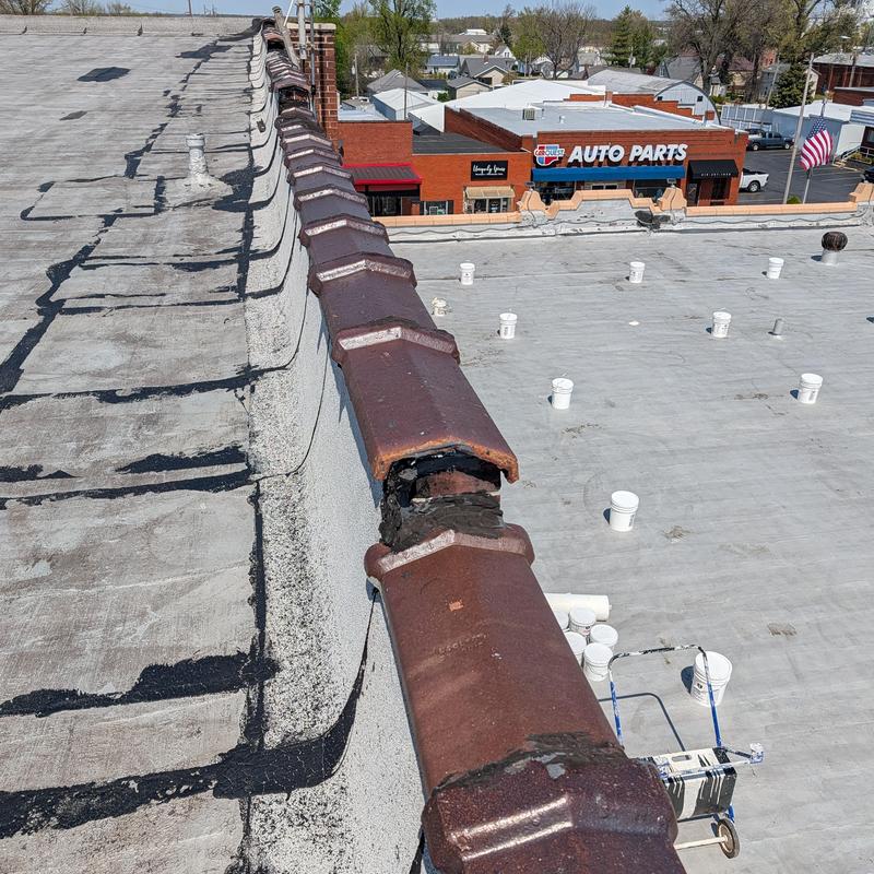 Elastomeric flat commercial roof with ridge cap tiles
