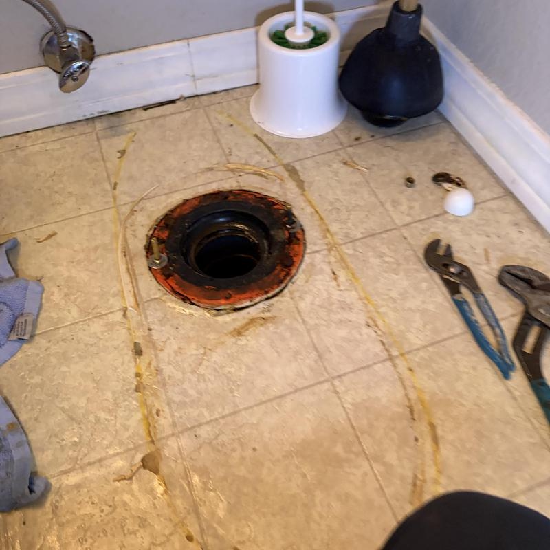 Toilet flange with removed toilet and plumbing tools nearby