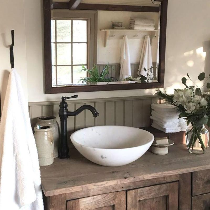 Marble basin with black faucet on wooden vanity