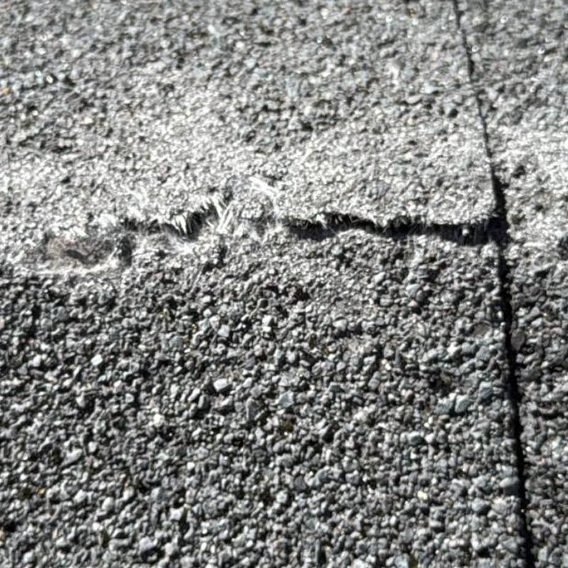 Asphalt shingle roof close-up showing crack damage
