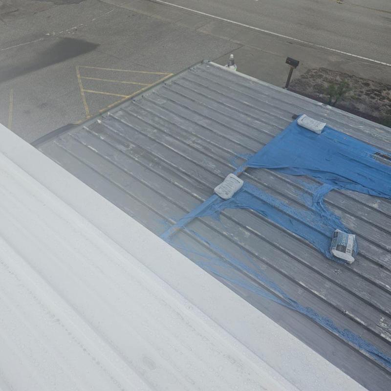 Metal roof with damaged coating and tarps in place