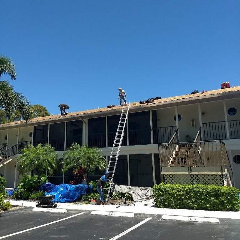 Shingle roof tear-off on Naples condo with ladder