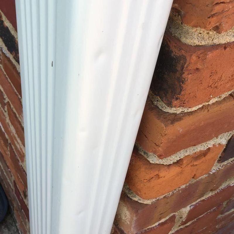 Vinyl downspout with minor hail dents on brick wall Vinyl downspout with minor hail dents on brick wall