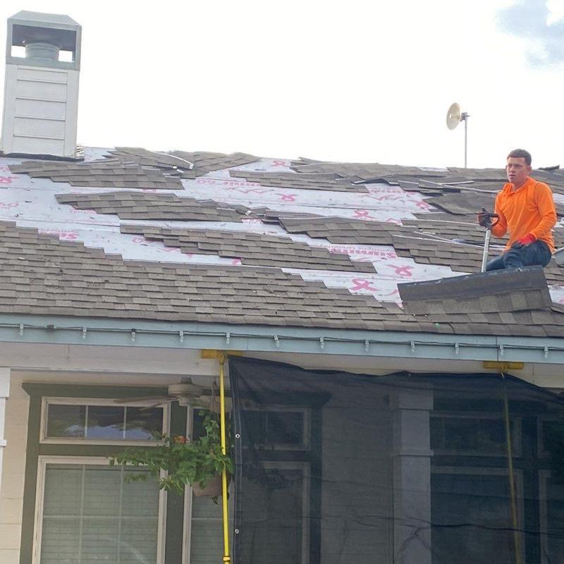 Asphalt shingle roof replacement with worker on roof Asphalt shingle roof replacement with worker on roof