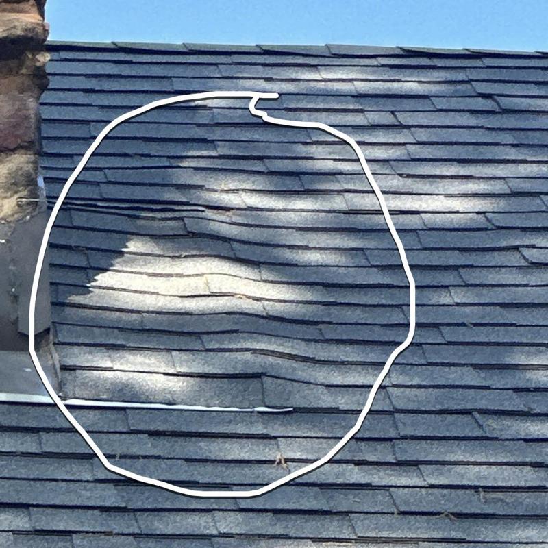 Asphalt shingles with warping damage on roof near chimney