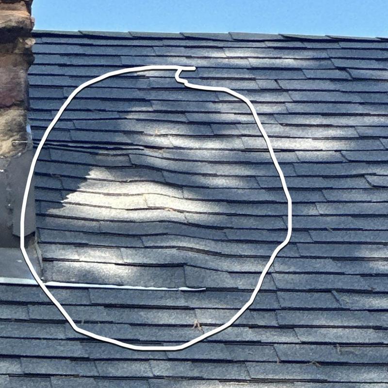 Asphalt roof shingles with visible warping and damage