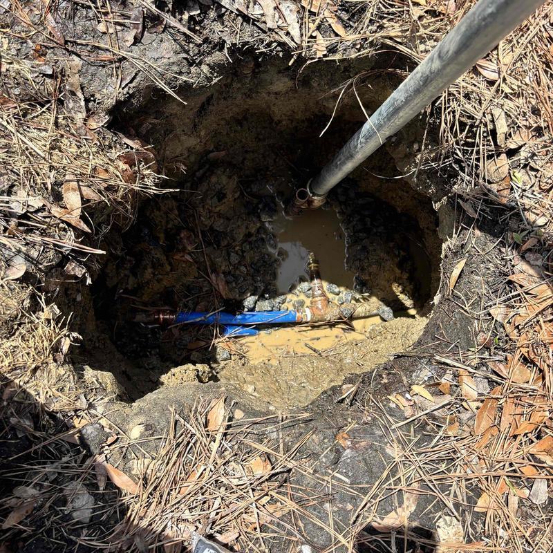 Water line with piping in muddy excavation pit