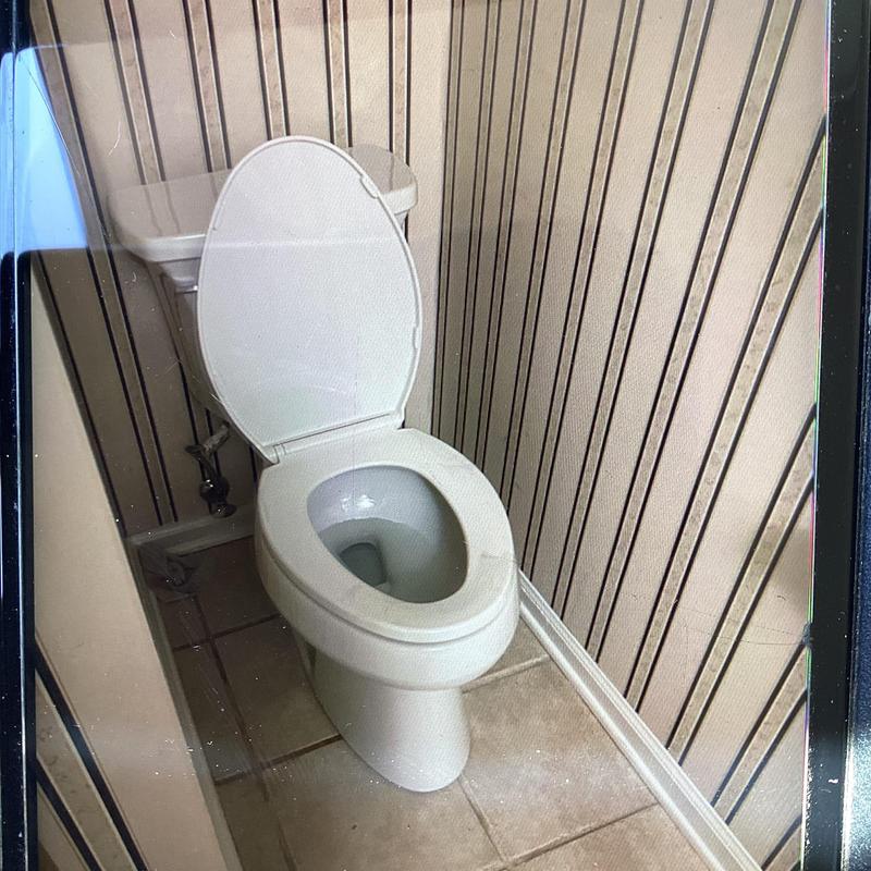 Toilet with open lid in bathroom corner