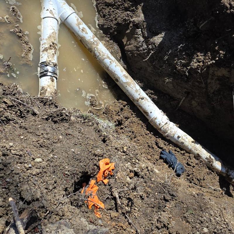 4-inch PVC septic bypass pipe installation in muddy trench