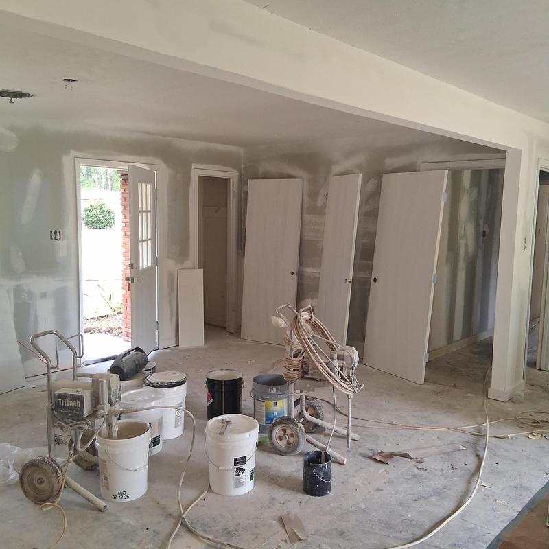 Drywall and door installation with painting equipment in room