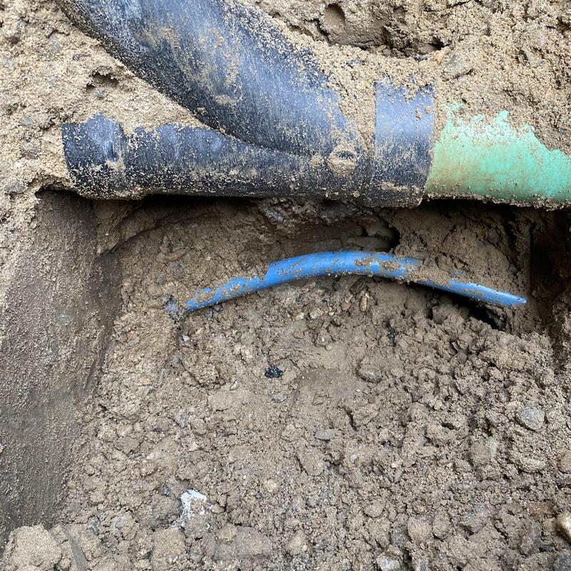 Blue water service line exposed in dirt trench repair Blue water service line exposed in dirt trench repair