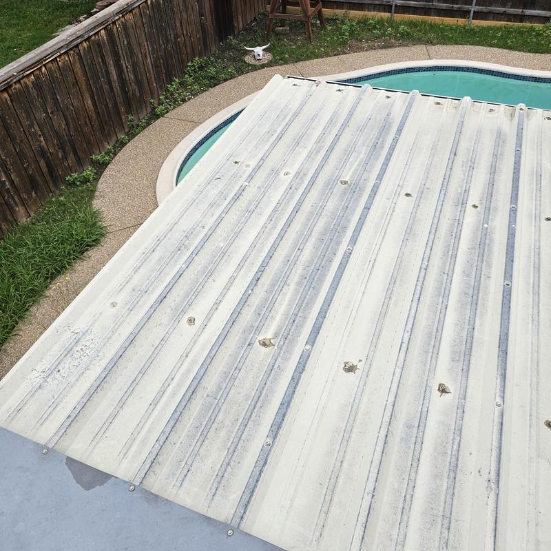 Metal patio roof with hail impact damage near pool
