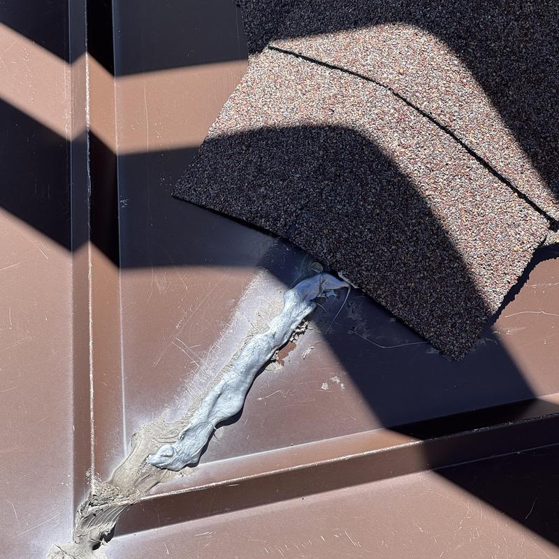 Metal roof flashing sealed with roofing cement and shingle