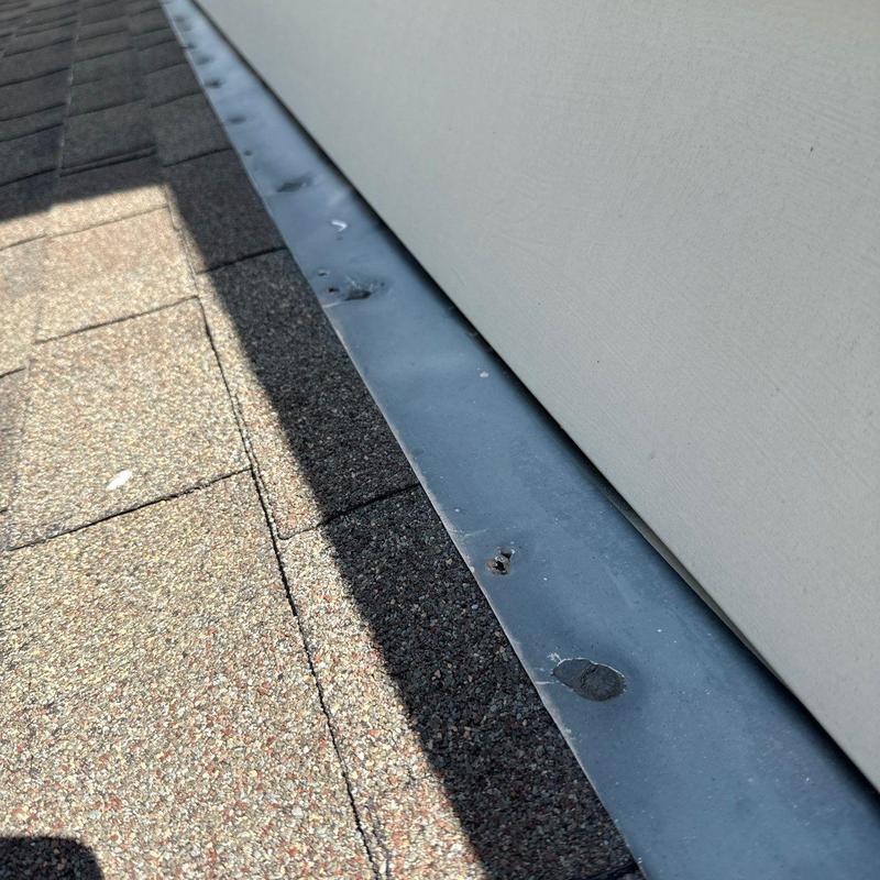 Metal flashing with hail damage on roof shingles