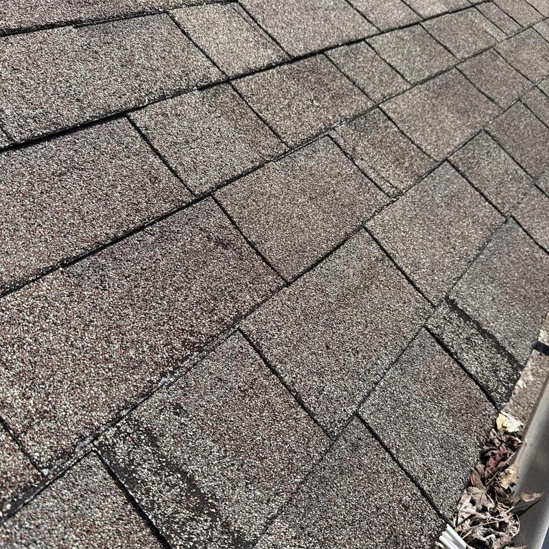 Asphalt shingles with hail impact damage on roof surface