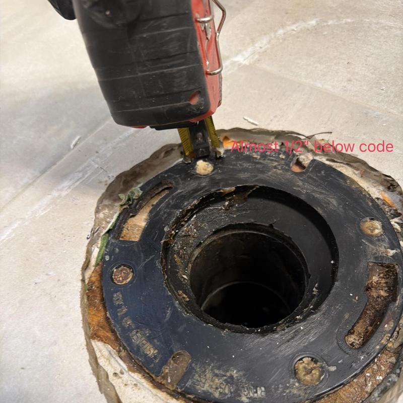 Toilet flange below grade with measuring tape