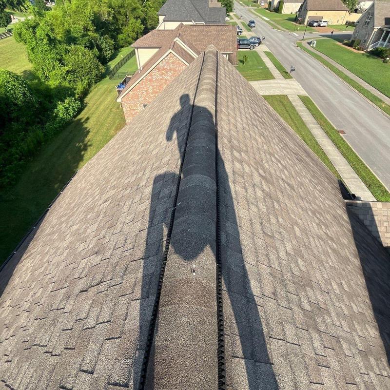 Asphalt shingle roof ridge with shadow and neighborhood view