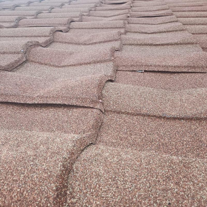 Stonecoated steel roof with damaged panels and screws