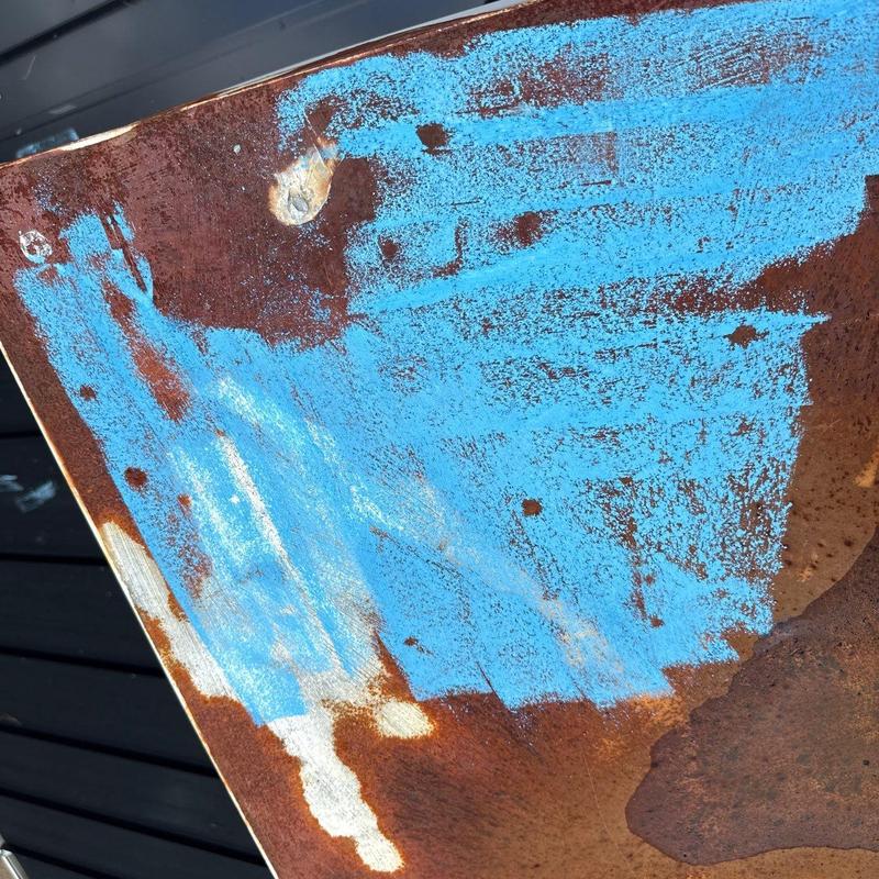 Rust-damaged metal flashing with blue coating remnants
