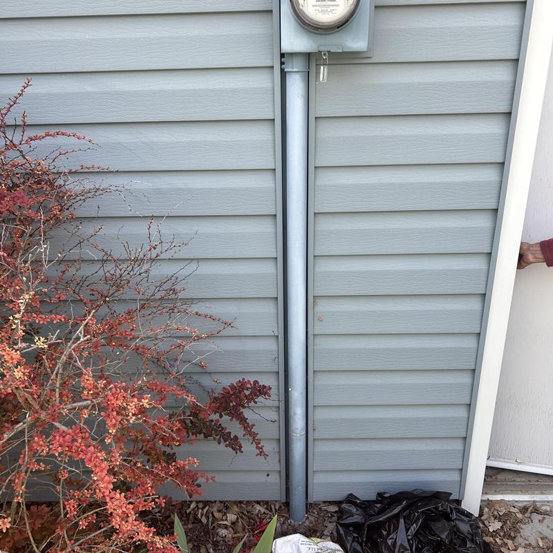 Electric meter with conduit on house siding exterior