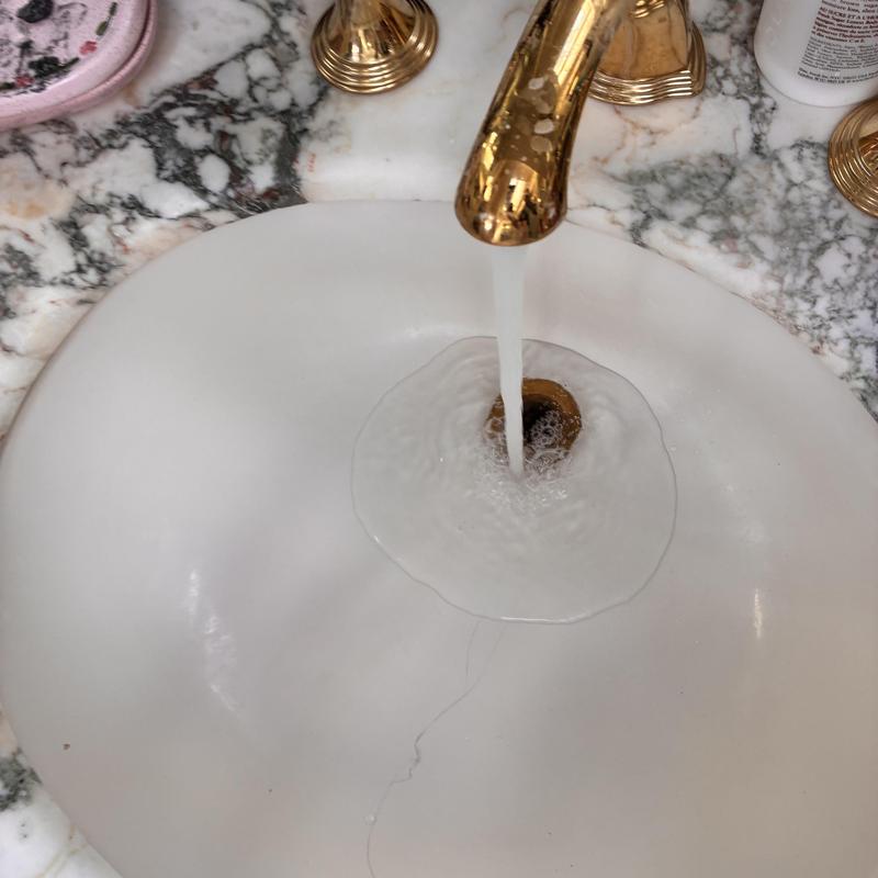 Bathroom sink drain clearing with flowing water