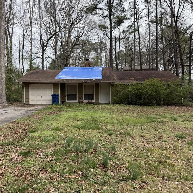 Roof with blue tarp covering damaged area