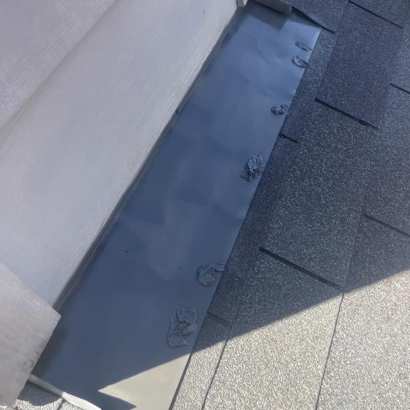 Wall flashing with sealant repairs on shingle roof