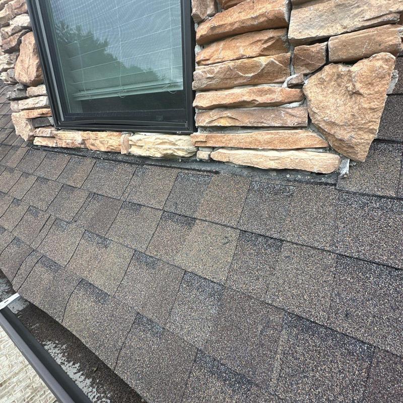 Asphalt shingle roof under window with stone trim
