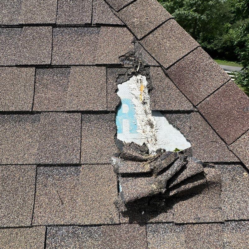 Roof shingles with hail damage and bare underlayer exposed