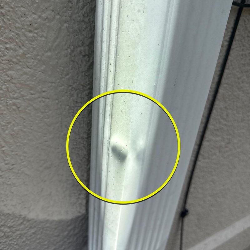 Aluminum gutter dent with impact damage in yellow circle