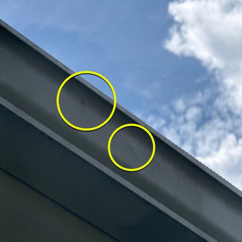 Metal gutter with dents marked for inspection