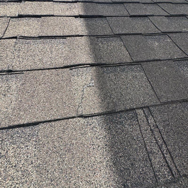 Asphalt shingles with visible hail damage and cracking