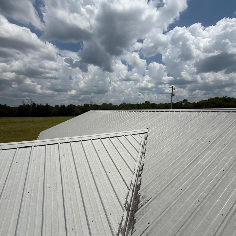 Metal roof panels with valley and fasteners under cloudy sky