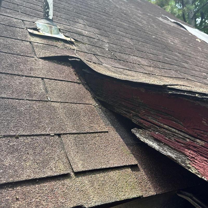 Shingles with hail damage and lifted edges on roof