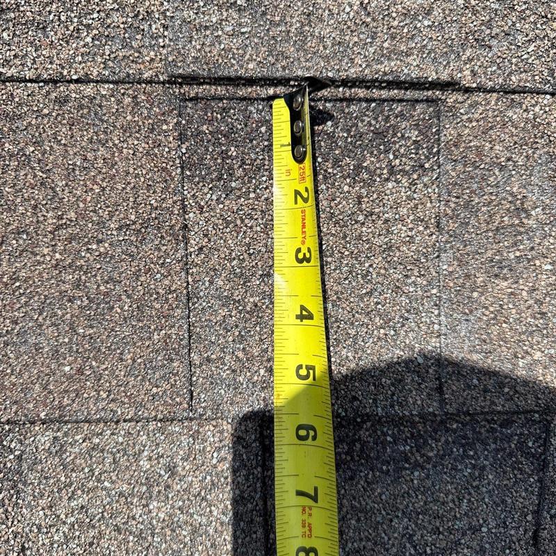 Asphalt shingles with measuring tape showing dimensions
