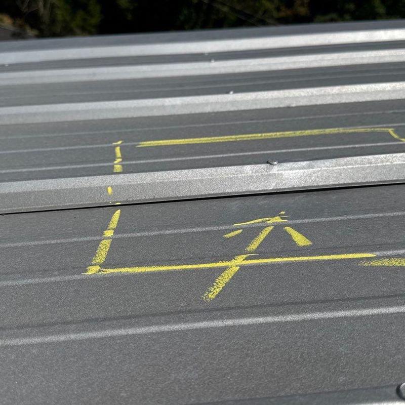 Metal commercial roofing with yellow chalk damage marks
