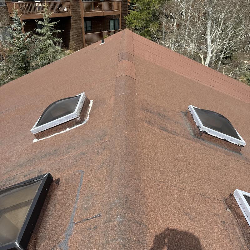 Skylight sealing with caulking on shingle roof ridge